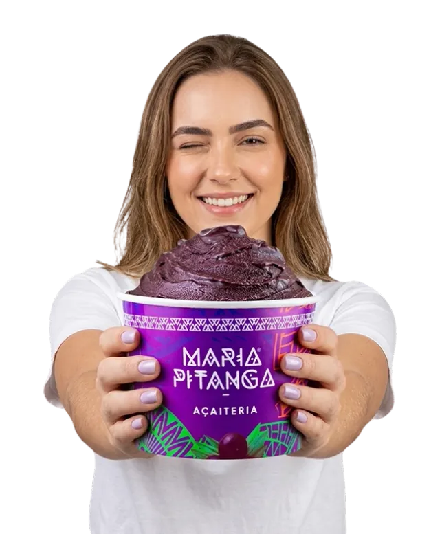 Mulher sorridente a estender um copo de açaí Maria Pitanga